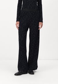 Zwarte wijde broekspijpen gemaakt van zachte stof met een subtiel gespikkeld patroon; heeft een gladde zwarte tailleband voor extra comfort.