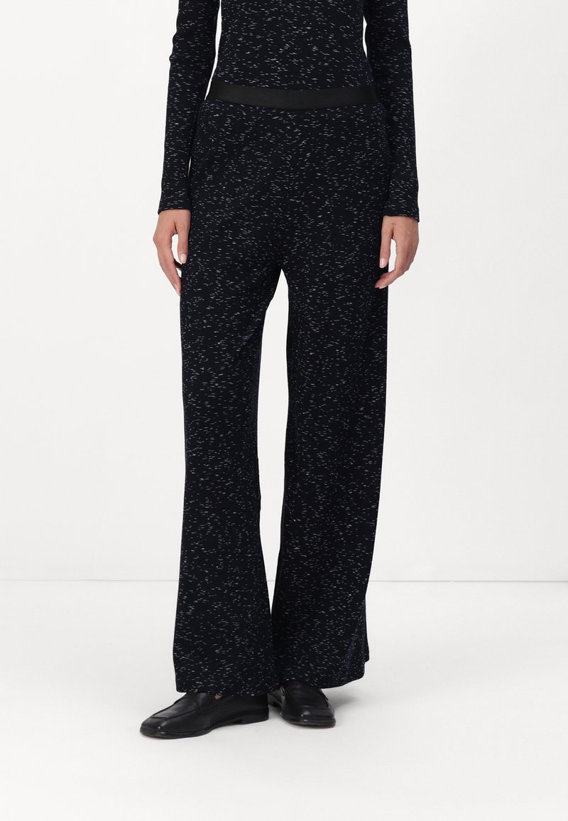 Zwarte wijde broekspijpen gemaakt van zachte stof met een subtiel gespikkeld patroon; heeft een gladde zwarte tailleband voor extra comfort.