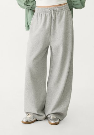 Gray wide-leg sweatpants with an elastic waistband and drawstring detail, made from soft fabric. Paired with shiny silver sneakers.