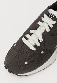 Graue Wildleder-Sneaker mit weißen Schnürsenkeln, Netzeinsätzen und kleinen gestickten Blumenmotiven; runde Zehenpartie und schwarze Gummisohle.