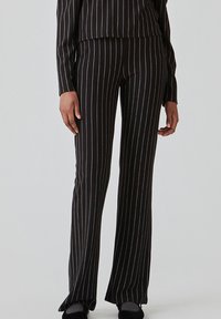 Sorte flared bukser med hvide lodrette striber, lavet af et glat stof, med en tætsiddende talje og let stræk for komfort.