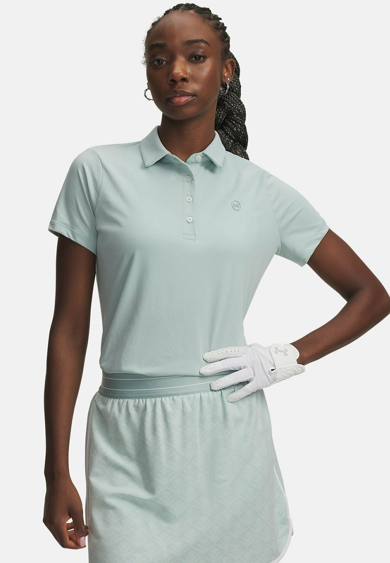 Ανοιχτό μπλε πόλο με κοντά μανίκια και τρία κουμπιά, συνδυασμένο με μια φούστα σε αντιστοιχία που έχει μοτίβο από διαμάντια. Λευκό γάντι γκολφ στο αριστερό χέρι.