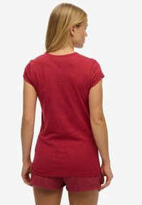 Rood katoenen T-shirt met korte mouwen, ronde hals en een rechte snit. De textuur lijkt zacht, met een subtiele glans. Korte bijpassende korte broek.