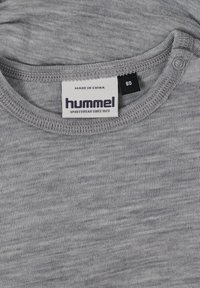 Grå, texturerad sporttröja med rund halsringning, etikett tryckt med "hummel", storlek 80, och sömmar synliga runt kragen.