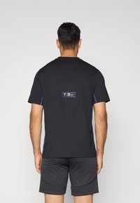 Zwarte T-shirt van katoen met korte mouwen, voorzien van contrasterende paarse zijkanten en een logo-embleem op de rug.