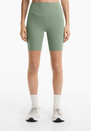 Hoge taille, figuuraccentuerende fietsbroekjes in een gedempte groen kleur, gemaakt van een gladde, rekbare stof met een lengte tot halverwege de dijen.