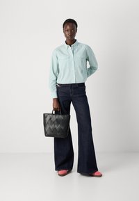 Ljust blårandig skjorta med knappar, mörka utsvängda jeans, svart vadderad handväska och rosa skor. Avslappnad och funktionell outfitdesign.