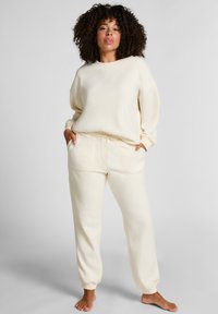 Crème-kleurige loungeset van zachte stof; bevat een relax-fit sweatshirt en tapervormige joggingbroek met een elastische tailleband en trekkoord.