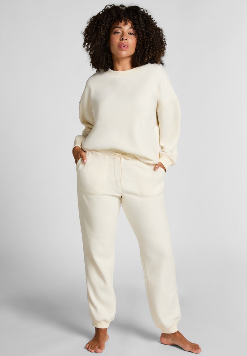 Crème-kleurige loungeset van zachte stof; bevat een relax-fit sweatshirt en tapervormige joggingbroek met een elastische tailleband en trekkoord.