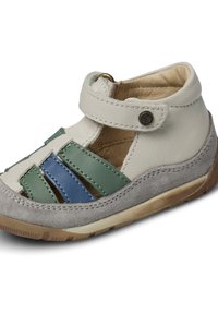 Sandale en cuir gris clair avec des rayures synthétiques vertes et bleues. Elle est dotée d'une sangle avec un fermoir à bouton et d'une semelle en suède gris texturé.