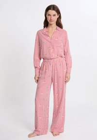 Rode en witte gestreepte pyjama set met een colbert met knopen en losse broek met een speels patroon. Zacht materiaal, comfortabele pasvorm.