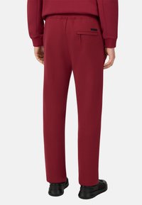 Pantalones de chándal burdeos hechos de una suave mezcla de algodón, con una cinturilla elástica, un bolsillo trasero y un diseño de pierna ajustada.