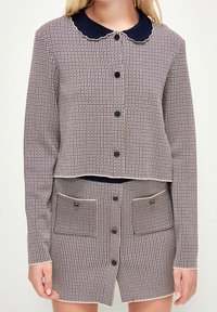 Vävt tvådelat set med en cropped jacka och kort kjol. Röd, vit och marinblå rutmönster med scalloped krage och knappdetaljer.