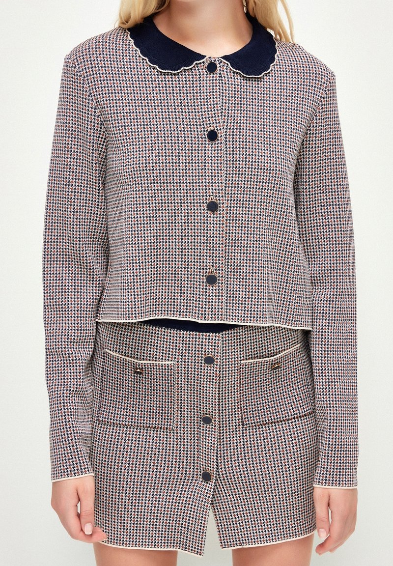 Vävt tvådelat set med en cropped jacka och kort kjol. Röd, vit och marinblå rutmönster med scalloped krage och knappdetaljer.