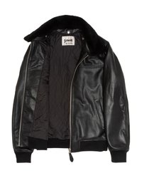 Zwarte leren jas met gewatteerde voering, zwarte schapenwollen kraag, geribde manchetten en onderrand, en zilveren rits aan de voorkant die gedeeltelijk open is.