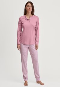 Roze lange mouwen henley-top met een ronde kraag en knoopsluiting, gecombineerd met lichtroze gestreepte pyjamabroek in een ontspannen pasvorm.