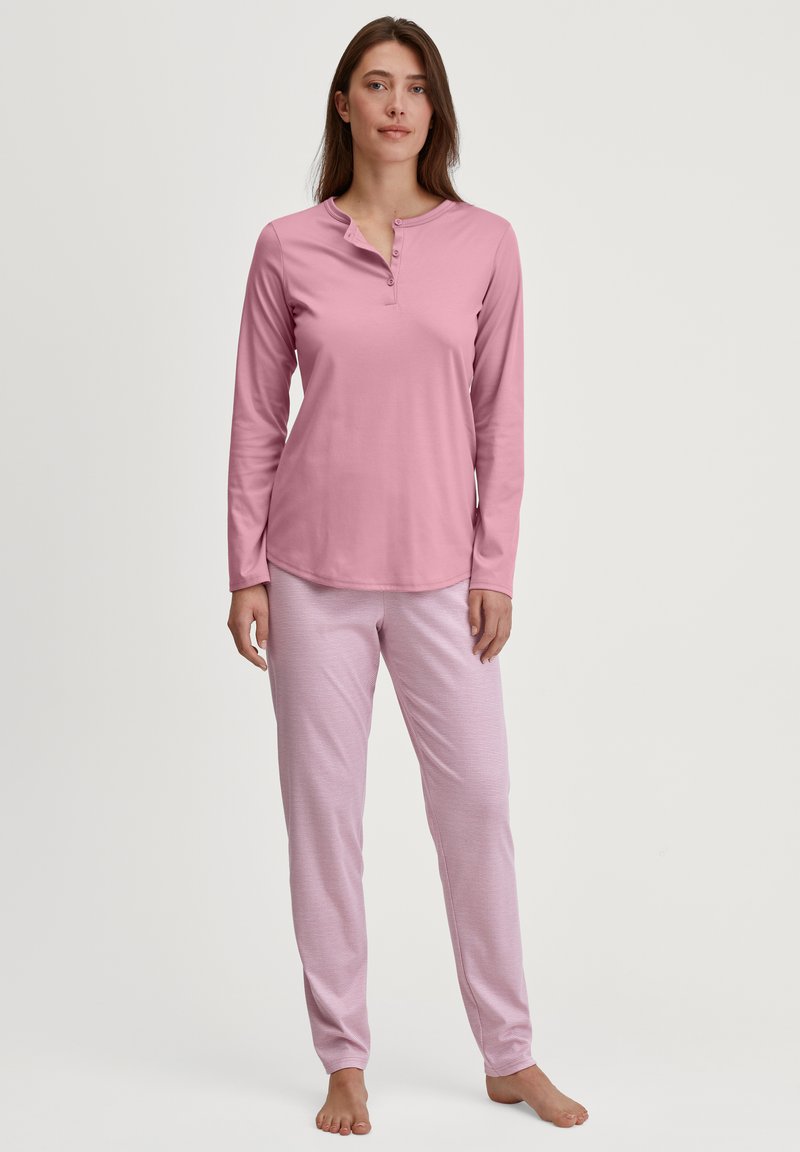 Roze lange mouwen henley-top met een ronde kraag en knoopsluiting, gecombineerd met lichtroze gestreepte pyjamabroek in een ontspannen pasvorm.