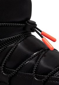 Bota negra con cordones reflectantes asegurados por un toggle negro y dos extremos de cordón de plástico naranja contra un fondo blanco.