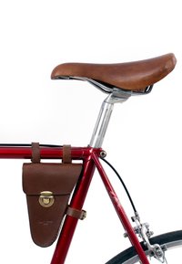 Rood fietsframe met een bruin lederen zadel en een bijpassende leren tas met een messing sluiting die aan het frame is bevestigd.