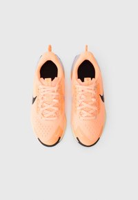 Zapatillas deportivas ligeras en malla naranja brillante con acentos negros, punta redonda y superficie texturizada. Presenta cordones tradicionales y una lengüeta.