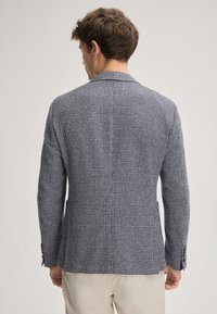 Blazer a scacchi in tessuto navy e bianco, con un design strutturato, colletto a rever e due tasche frontali. Fit su misura con una sottile texture.