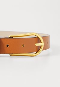 Ceinture en cuir marron avec une texture lisse et une boucle ovale en ton or. La ceinture possède de petits trous pour l'ajustement et un bord contrastant.