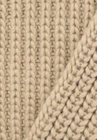 Gruby dziany materiał w jasnym beżu z wyraźnym pionowym prążkowaniem, o miękkiej, teksturowanej powierzchni i subtelnymi szarymi prążkami.