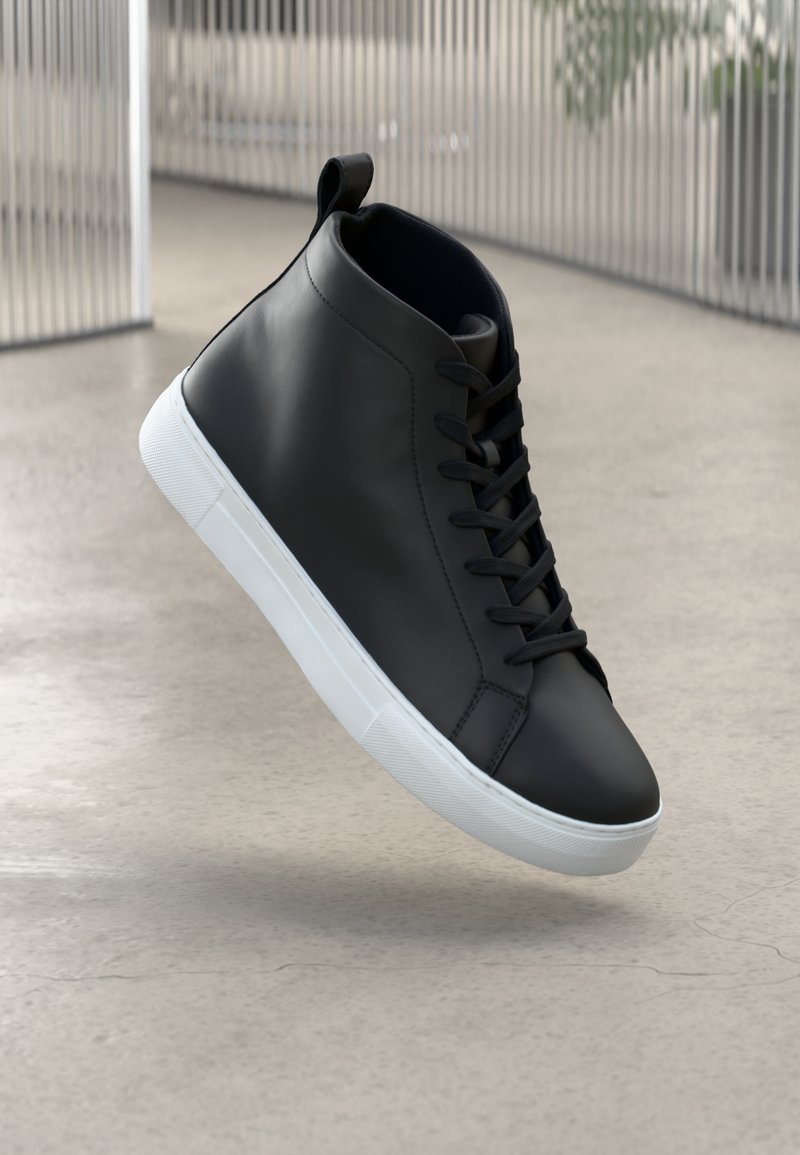 Sorte lær høy-top sneakers med hvit gummisåle, snøring foran og en løkke nederst på hælen. Glatt tekstur med minimal søm.