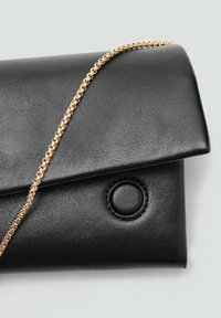 Zwarte leren clutch met een puntige klep, voorzien van een gouden kettingband en een cirkelvormige knoopdetail. Glad textuur, minimalistisch ontwerp.