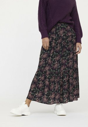 Jupe maxi florale avec un fond vert foncé et des roses violettes, design en étages et tissu doux, portée avec des baskets blanches.