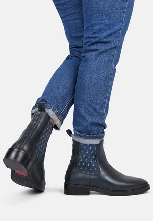 Czarne skórzane botki do kostki z niebieskimi wzorzystymi panelami bocznymi przedstawiającymi kotwice, gumowymi podeszwami oraz niskim, warstwowym obcasem.