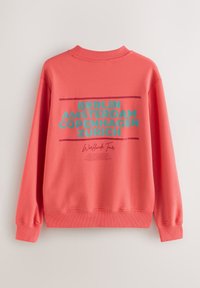 Felpa corallo con collo e polsini a costine, con scritte audaci: "BERLINO AMSTERDAM COPENAGHEN ZURIGO" e "Worldwide Tour" in turchese e marrone scuro.