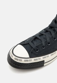 Mustekin musta jalats GORE-TEX märkega, kummist varbaga ja tekstuurse kummist tallaga. Omab sirgeid musti paelu ja silmadele.