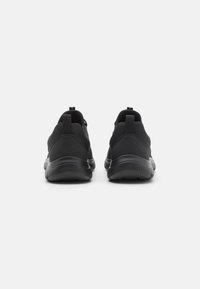 Black athletic shoes with a mesh and synthetic material upper. Features a cushioned sole and looped heel tab for easy wear.