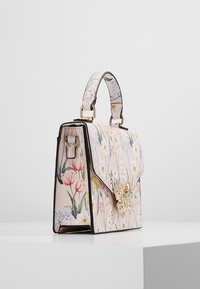 Blomstret håndtaske med en struktureret form, pastelfarvet pink materiale, gylden sommerfugleaccent og en aftagelig rem med et mønstret for.