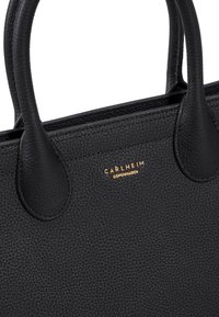 Borsa a tracolla in pelle nera con superficie texture, dotata di due manici arrotondati e marchio dorato "Carlheim Copenhagen" nella parte anteriore.