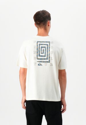 Crème t-shirt met een spiraalvormige graphic in blauw, geel en zwart. Bevat de tekst "VIND JE ZIEL" rondom het ontwerp. Korte mouwen, relaxed fit.