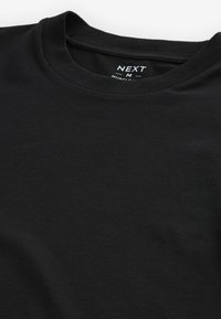 T-shirt nera con scollo rotondo e maniche corte, etichettata "NEXT M Muscle Fit" all'interno del collo posteriore.