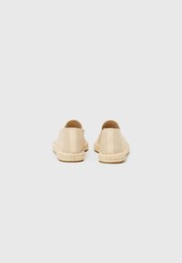 Beige espadrilles met een textiel bovenwerk, elastische zijkanten en geweven jute zolen. Eenvoudig ontwerp zonder zichtbare patronen of accenten.