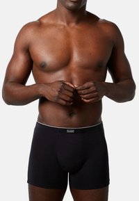 Boxer briefs neri con una vita bianca e branding. Tessuto morbido, forma aderente e design frontale sagomato per il supporto.