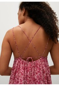 Robe sans manches à motif floral rose, présentant un dos froncé avec un lien et des bretelles croisées. Tissu léger et fluide.