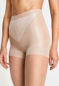 Beige muotoilevat shortsit, jotka on valmistettu sileästä, venyvästä materiaalista, korkea vyötärö ja teksturoituneet, joustavat nauhat reisissä.