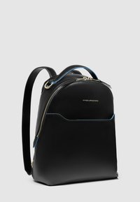 Mochila de cuero negro con acabado liso, forma curva, herrajes dorados, detalle de cremallera azul y un bolsillo frontal. Doble asa superior.