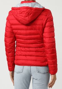 Chaqueta roja acolchada con diseño acolchado, capucha y forro interior gris con patrón, con mangas largas y silueta ajustada.