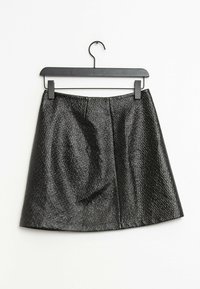 Schwarzer Minirock mit strukturierter Oberfläche, der ein ausgestelltes Design aufweist. Er hängt an einem schwarzen Kunststoffhaken und zeigt sichtbare Nähte.
