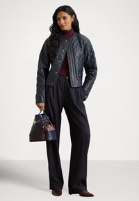 Παγωμένο μαύρο δερμάτινο μπουφάν με στρογγυλεμένο γιακά, συνδυασμένο με μαρουν ζιβάγκο, γκρι υφασμάτινο παντελόνι με ρίγες και δίχρωμη τσάντα χειρός.