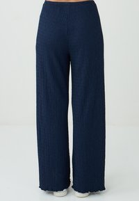 Marine wijde pijpen broek van textuurstof, met een gouden tailleband en een geschulpte zoom, geschikt voor casual wear.
