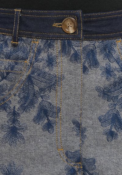 Džínová tkanina s modrou kvetinovou výšivkou, hnedým gombíkom, žltým prešitím a pútkami na opasok na páse džínsov.