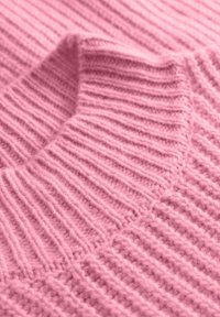 Teksturowana różowa dzianina z wzorem pionowych i poziomych prążków, charakteryzująca się miękkim, przytulnym wyglądem i lekką puszystością.