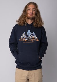 Hoodie bleu marine en coton ; arbore un graphique de montagne triangulaire dans des nuances de bleu, orange et marron. Poche kangourou à l'avant.